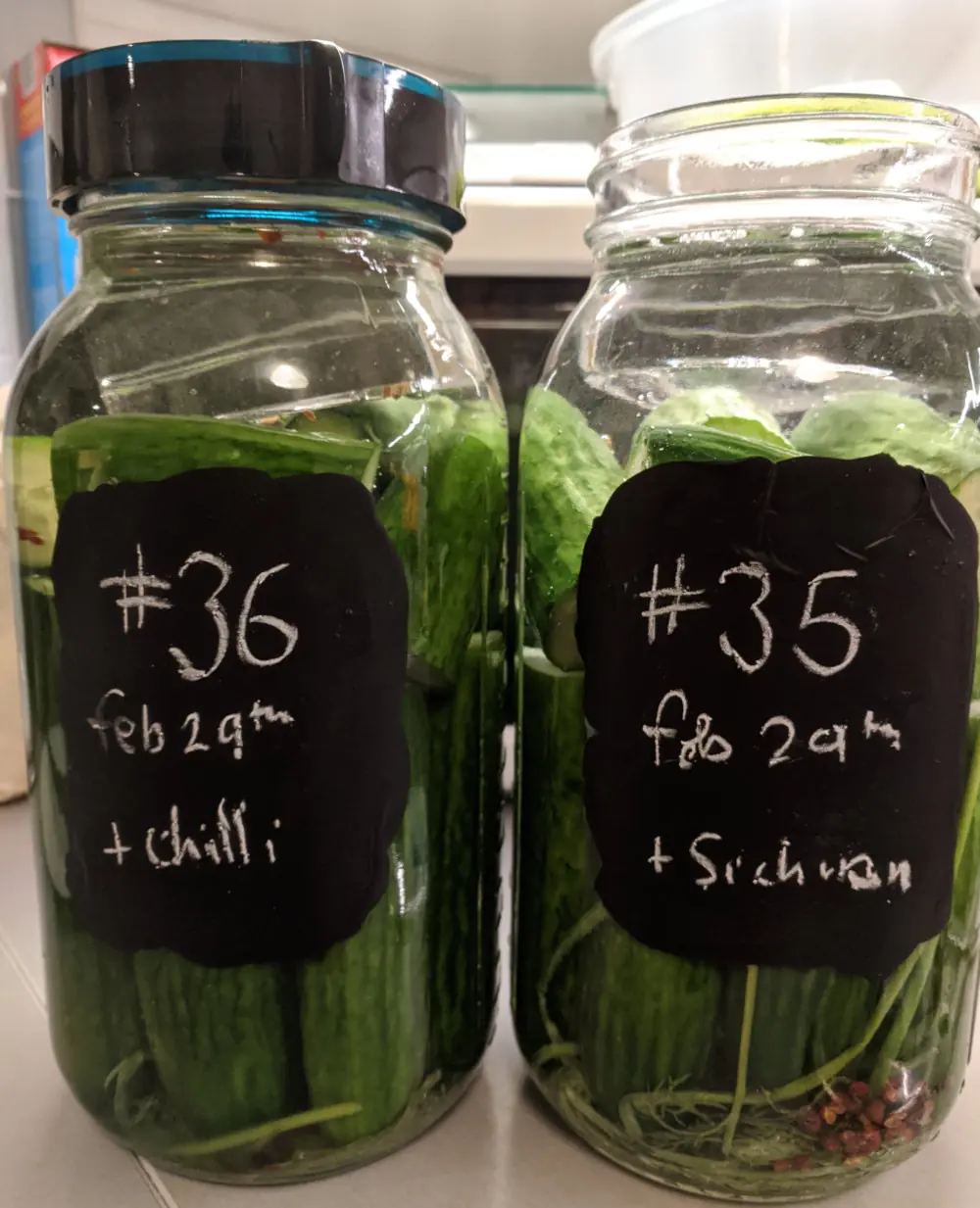 Two mason jars, full of fermenting cucumbers.