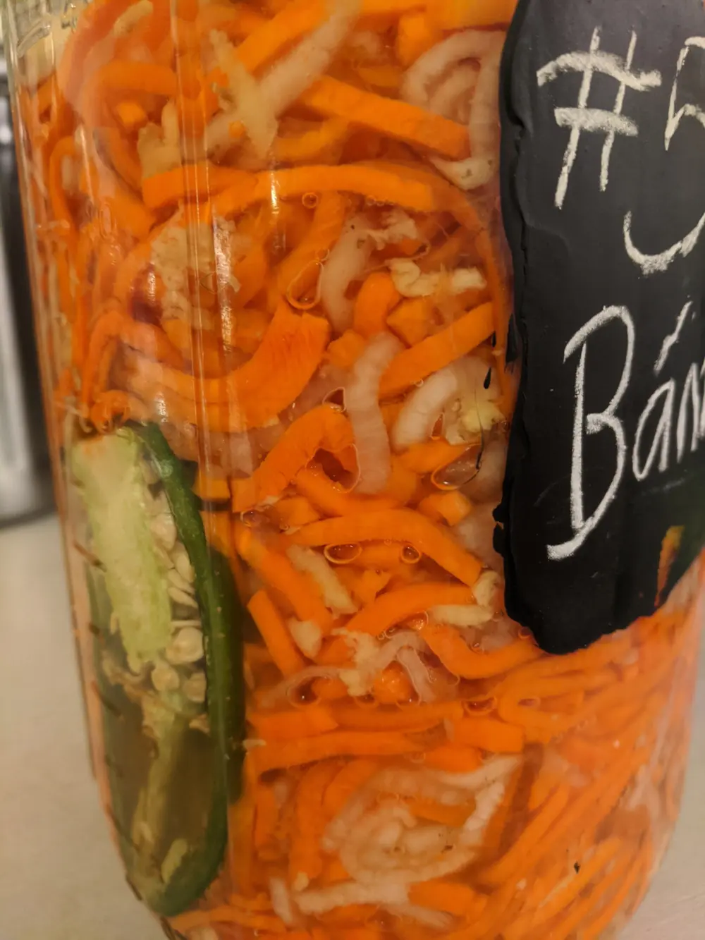 Spiralized carrots & daikon radish, with halved Jalapeno, in the brine ready to ferment.